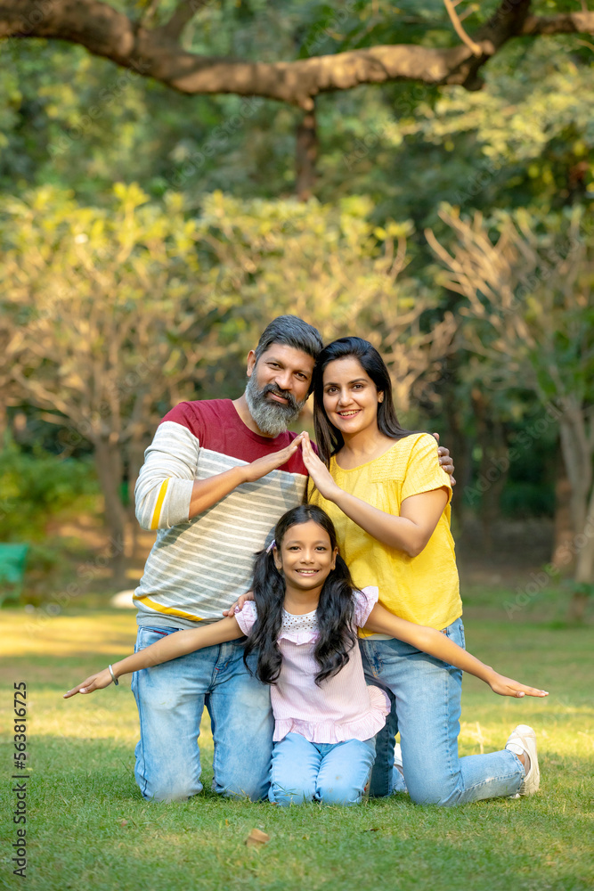 Fototapeta premium Young indian couple making home shape with hand with her daughter at park.