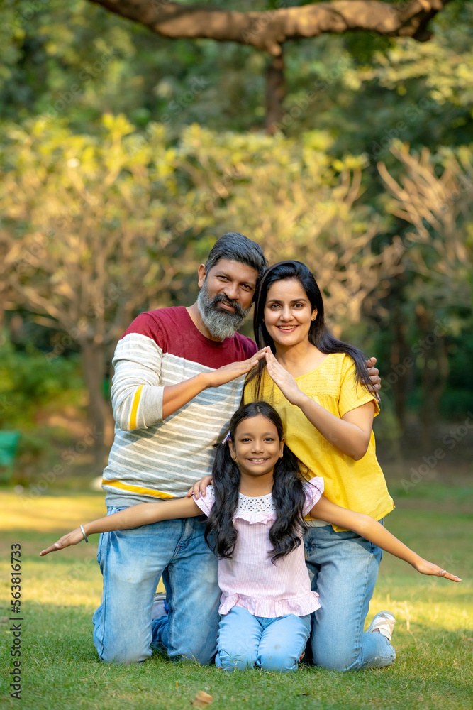 Fototapeta premium Young indian couple making home shape with hand with her daughter at park.
