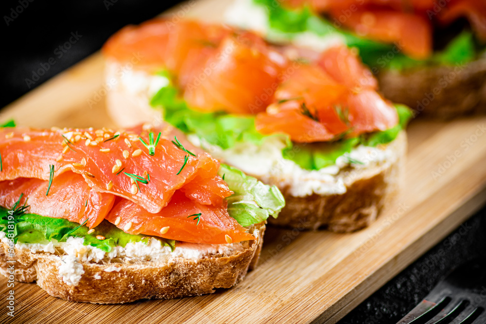Sandwich with pieces of salmon on a cutting board. Sandwich with pieces of salmon on a cutting board.