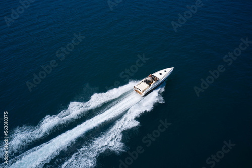 Large high speed motor white boat with people at high speed moving diagonally