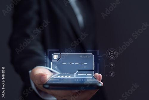 Businessman is using electronic credit card on mobile on virtual screen. The concept of using virtual credit cards in business and online commerce.