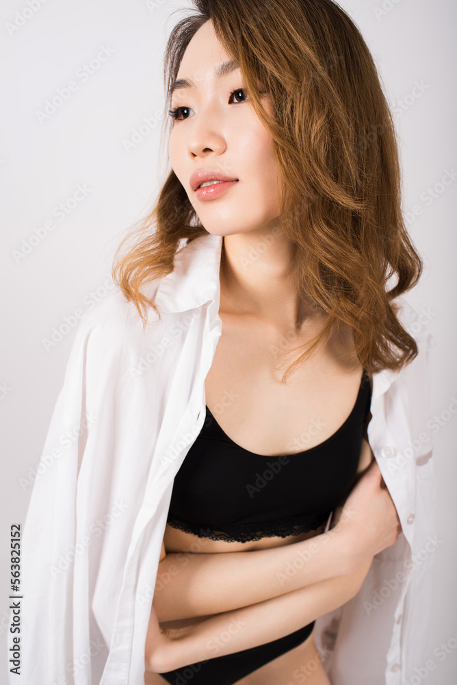 Young Asian girl in lingerie and shirt on a white background. Young Asian girl in lingerie and shirt on a white background.