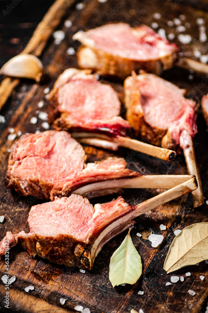 Rack grilled lamb on a cutting board with bay leaves. Rack grilled lamb on a cutting board with bay leaves.