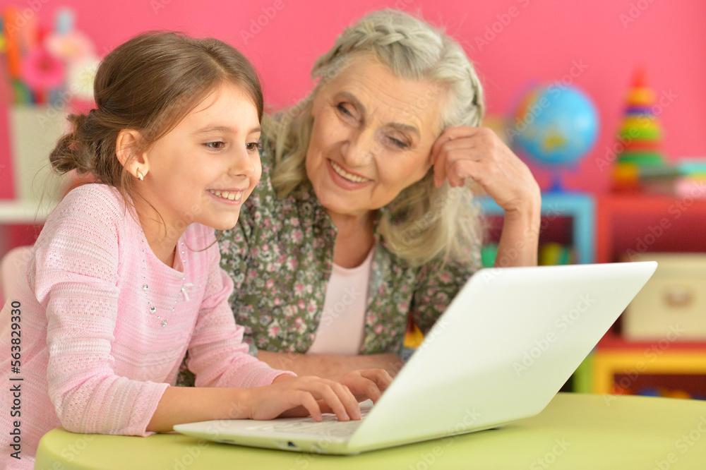 little girl with her grandmother playing computer game with laptop little girl with her grandmother playing computer game with laptop
