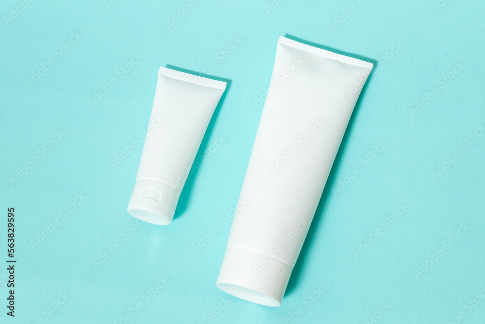 Two white colored cream bottle laying out next to each other on the top of a blue paper Two white colored cream bottle laying out next to each other on the top of a blue paper