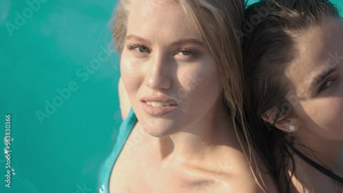 Top view video of two sexy women in swimsuit posing in outdoor swimming pool