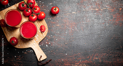 Tomato juice in glasses on a wooden cutting board. 