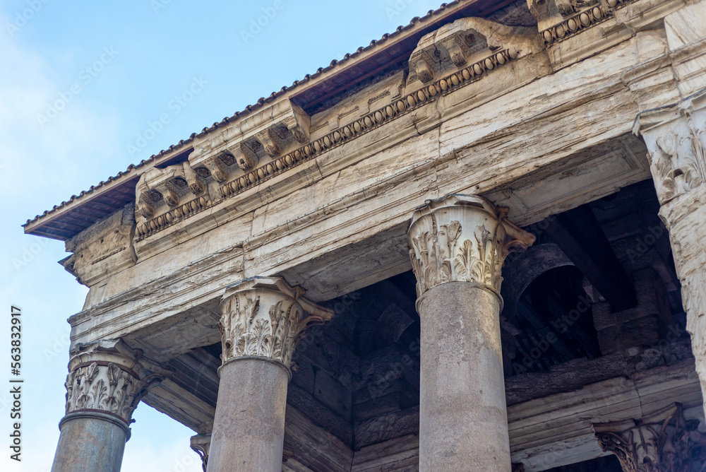 Fragment of columns and roof in Rome, in the blue sky. Important ancient buildings, fragment of the Temple.