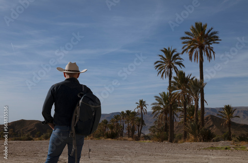 Rear view of adult man in cowboy hat walking on dirt road in desert. Almeria, Spain