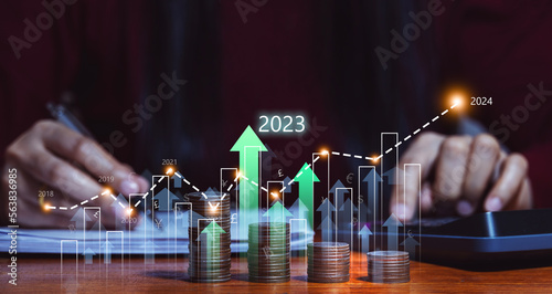 Businessman planning business growth in 2023 and beyond. with virtual holographic charts Calculate investment earnings and profits and increase them with positive growth indicators, stocks, profits.