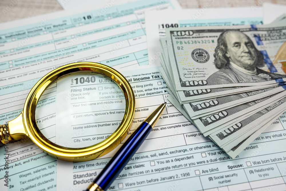dollar with magnifying glass on blank 1040 individual income tax form dollar with magnifying glass on blank 1040 individual income tax form