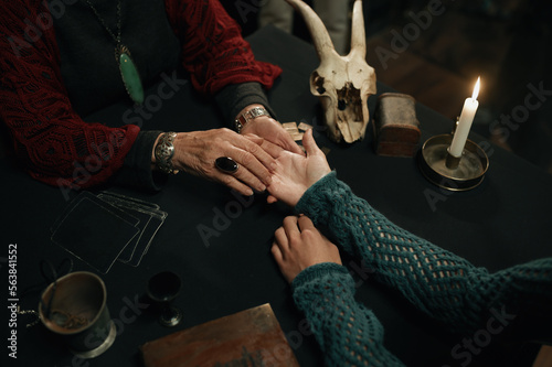 Top view fortune teller and client hands over table with spiritual attributes