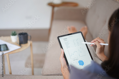 Work from home concept, Business women read financial data on tablet while lying on couch at home