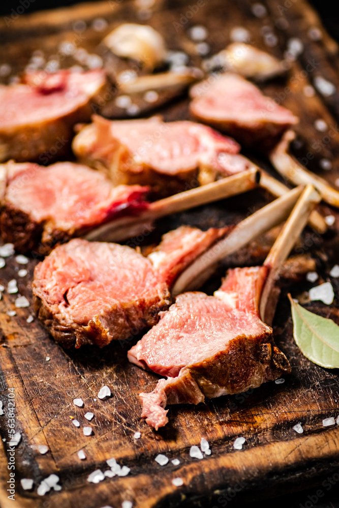Rack grilled lamb on a cutting board with bay leaves. Rack grilled lamb on a cutting board with bay leaves.