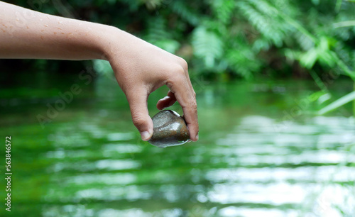 A woman's hand holding a zen basalt stone which she got from deep in the clear river water photo