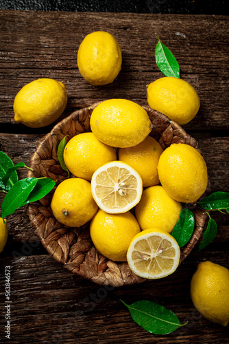 Halves and whole lemons with leaves in a basket. 