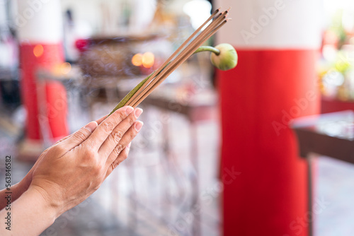 Action of human hand is holding incense stick and lotus flower during pay homage at the temple in Chinese new year event. Close-up and selective focus. photo