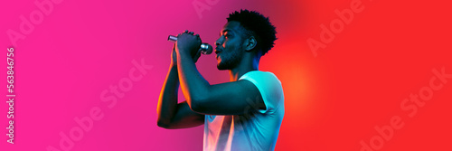 Singer. Horizontal banner with portrait of young african man over background in neon light. Music, beauty, fashion, youth concept. © Lustre