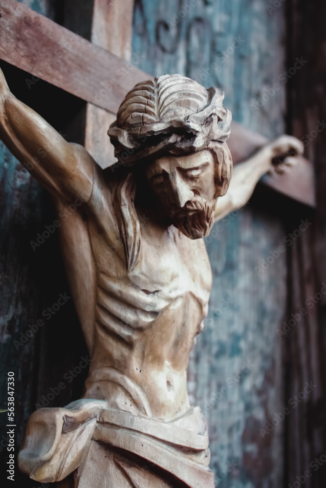 Jesus Christ crucified. Closeup an ancient wooden statue. Vertical image.