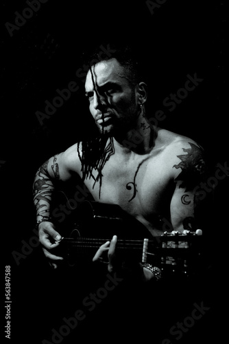 Man playing guitar and singing shirtless © gemaibarra
