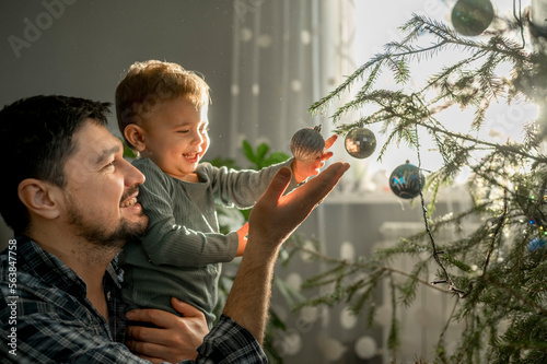 Happy father and son decorating Christmas tree at home