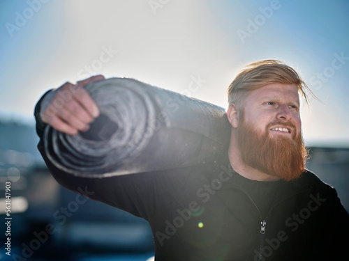 Smiling roofer with roofing felt roll on sunny day photo