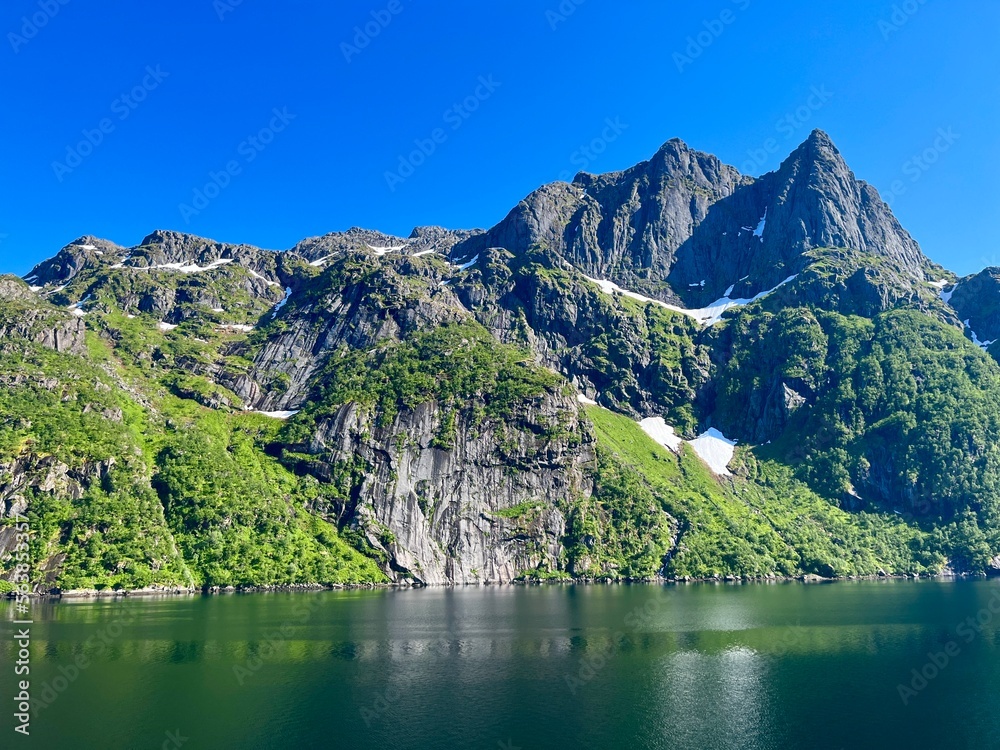 Beautiful fjords view in the blue sky, mountains reflection at the water surface, summertime 