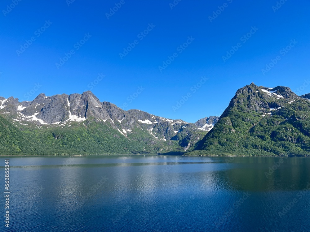 Beautiful fjords view in the blue sky, mountains reflection at the water surface, summertime 