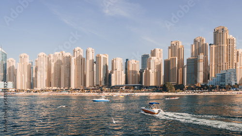 speedboat take tourists on the water in the bay near the coast of Dubai. Panorama of Dubai Marina in a summer day  UAE
