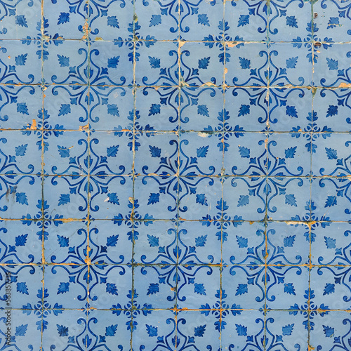 Damaged, faded, not corrected, vintage azulejos, glazed ceramic tiles with blue ornaments on building wall. Heritage Concept of traditional Portuguese art.