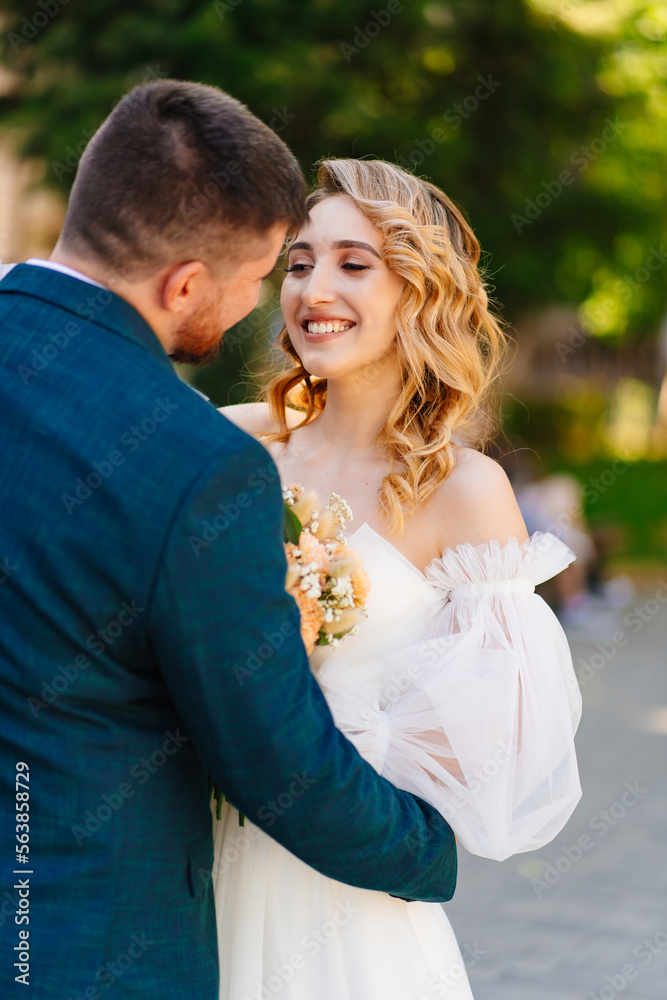 a bride in a delicate dress with a bouquet with the groom in the park