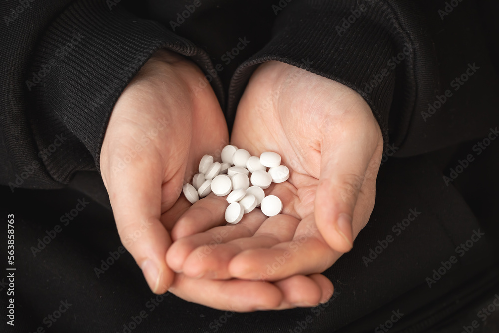 A lot of white pills in the hands of an adult man. A lot of white pills in the hands of an adult man.