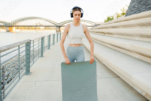 Young sports woman spreading her yoga mat outdoors © Drobot Dean