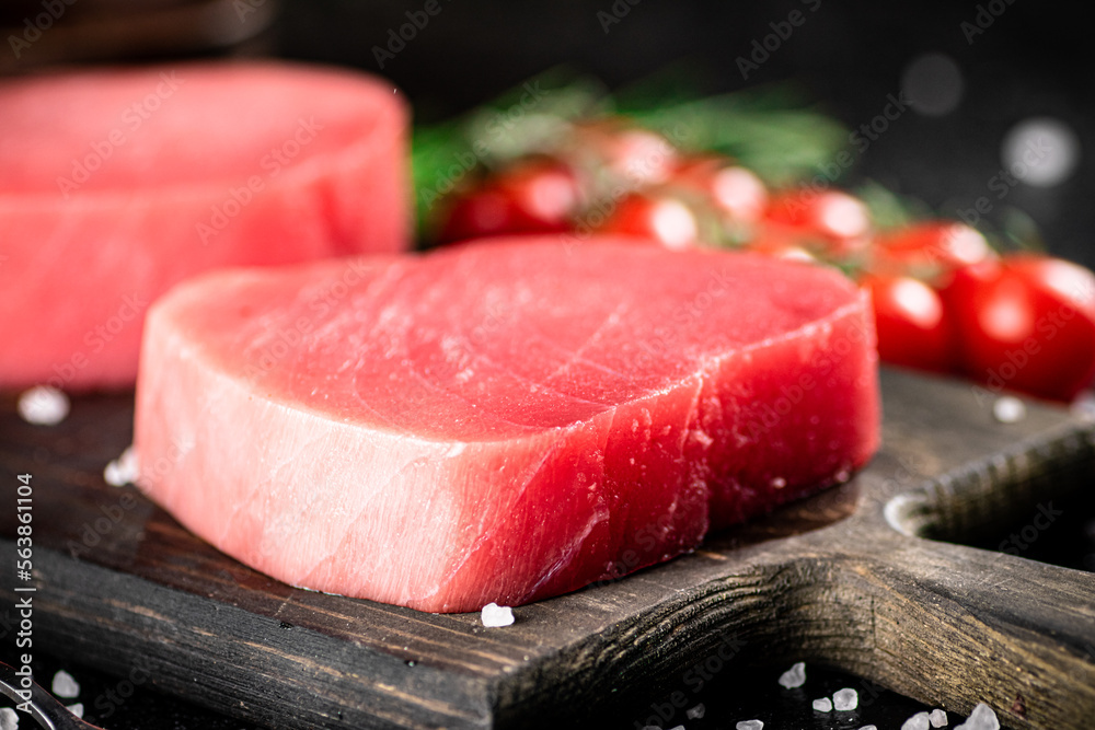 Fresh raw tuna on a cutting board with cherry tomatoes. 