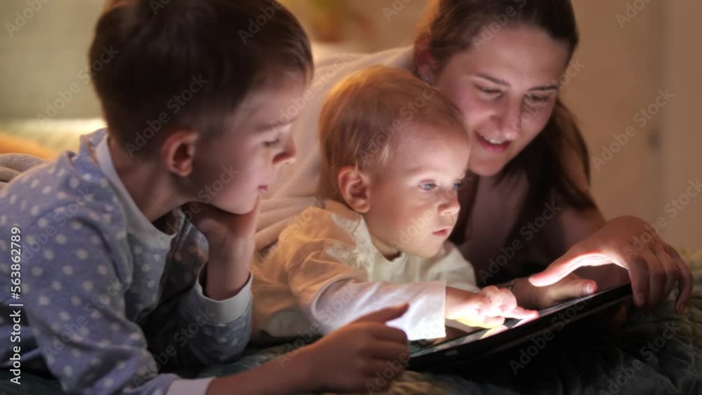 Cute baby boy and older brother playing with mother on tablet computer. Family having time together, parenting, happy childhood and entertainment Cute baby boy and older brother playing with mother on tablet computer. Family having time together, parenting, happy childhood and entertainment