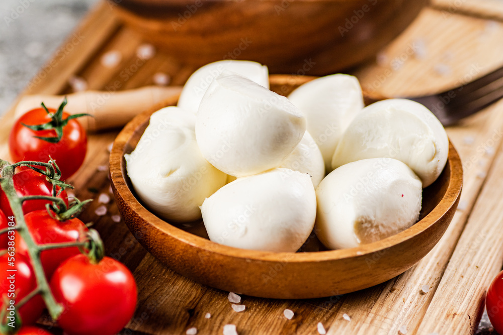Mozzarella cheese on a wooden cutting board with cherry tomatoes. Mozzarella cheese on a wooden cutting board with cherry tomatoes.