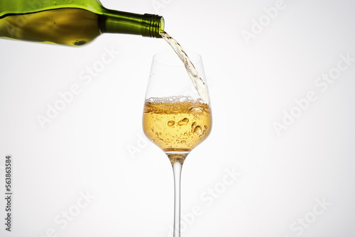 White wine pouring from green bottle, close up.