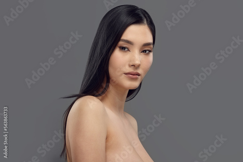 Asian female model with long dark hair looks to camera.