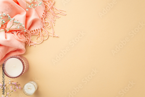 Hello spring concept. Top view photo of candles in glass holders pink cozy plaid and gypsophila flowers on isolated pastel beige background with empty space