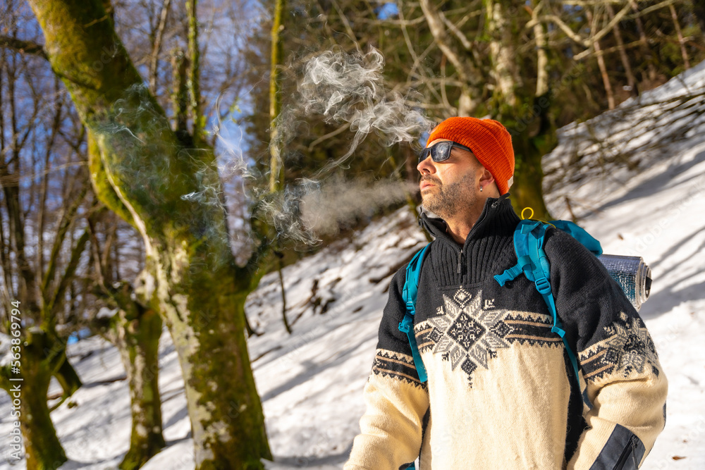 A man smoking a cigarette on a snowy hill in winter, enjoying the cold smoking