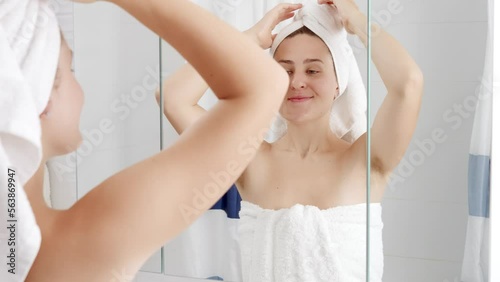 Portrait of beautiful smiling woman standing at mirror after having shower and lifting up arms. Concept of hygiene, natural beauty, feminity and body hair growth
