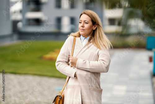 Billede på lærred A middle-aged woman is walking on the street on a chilly windy autumn day