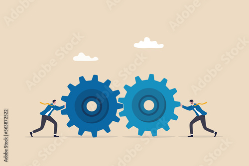 Teamwork and cooperation in a business setting, idea that working together can lead to success, collaboration or synergy concept, businessman push gear cogwheels together leading to success.