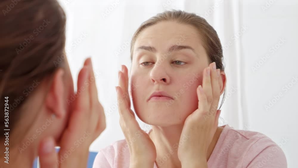 Closeup portrait of beautiful young woman checking for new wrinkles and pimples on her face skin. Concept of female aging, skin issues, facial treatment and care Closeup portrait of beautiful young woman checking for new wrinkles and pimples on her face skin. Concept of female aging, skin issues, facial treatment and care