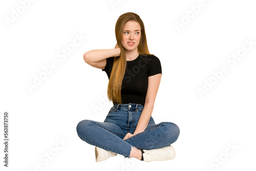 Young redhead woman sitting on the floor cut out isolated touching back of head, thinking and making a choice.