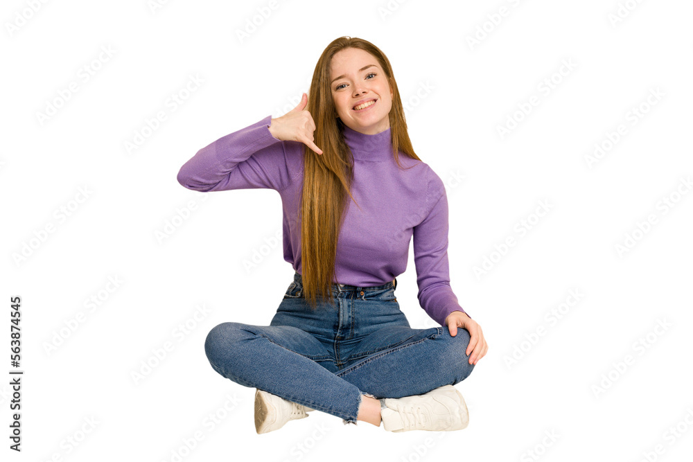 Young redhead woman sitting on the floor cut out isolated laughs out loudly keeping hand on chest.