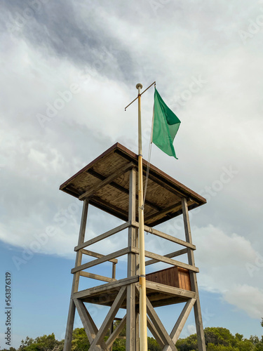 Lifeguard tower with green flag on the beach. Safe beach for swimming.