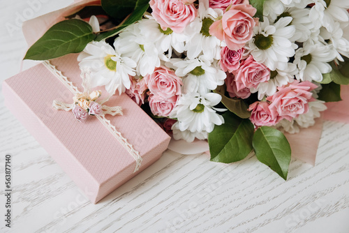 Fotótapéta Beautiful bouquet of rose and chrysanthemums flowers and pink gift box on white table background