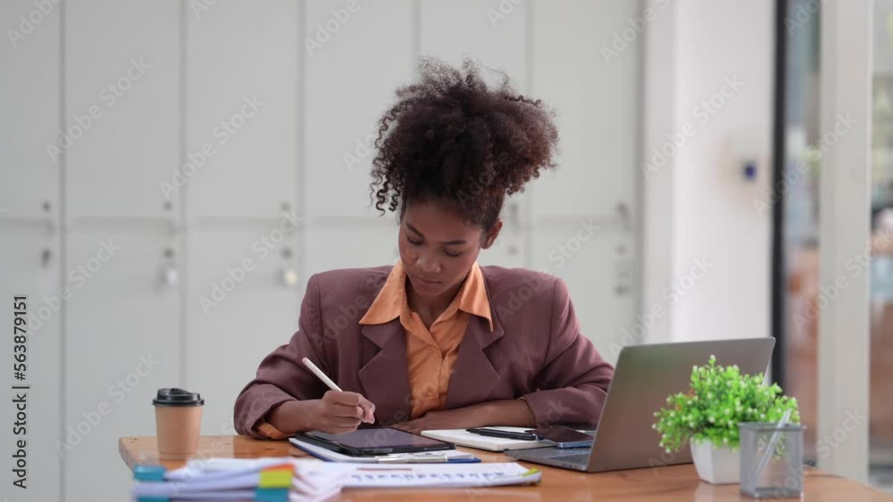 Young African female employee using stylus pen writing on digital tablet, working at office desk Young African female employee using stylus pen writing on digital tablet, working at office desk