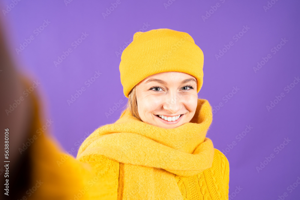 Selfie portrait of pretty woman wearing yellow winter clothes isolated on purple background